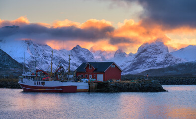 Wall Mural - red fishing boats on the sea, reflection in water, snowy mountains, colorful purple sky with pink cl