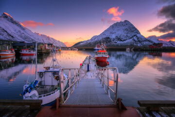 Wall Mural - red fishing boats on the sea, reflection in water, snowy mountains, colorful purple sky with pink cl