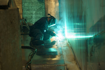 Poster - Welding sparks illuminate workshop as craftsman creates metal structure