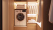 © Train arrival - Modern interior shows laundry nook with stacked washer and dryer, framed by light wood cabinetry. Folded towels, supplies, and hanging shirts enhance organized, minimalist look. Cozy, functional feel.