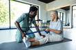 © zinkevych - Man physiotherapist guiding woman through leg exercise with resistance band for muscle recovery