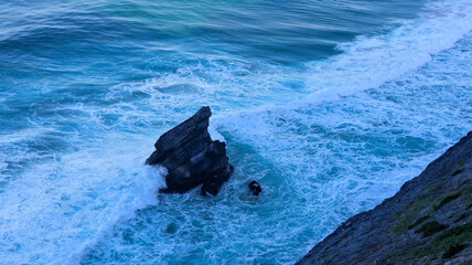 Wall Mural - a rocky beach in the evening with the waves in the foreground