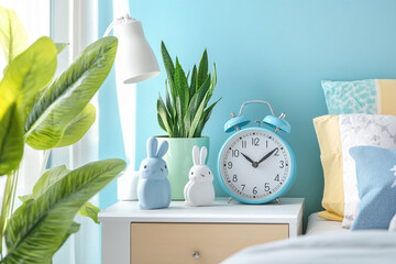 Poster - Minimalist bedside table with clock, plants, and ceramic rabbit figurines