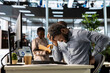 © DC Studio - Black enterprise worker takes a break and stretches his back muscles, dealing with a spinal spasm and headache. Male office employee trying to relieve pain and correct his position.