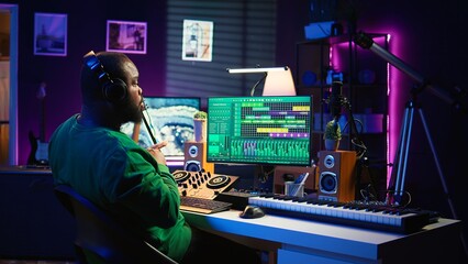 Poster - Confident music composer mixing sounds on digital audio software, creating a cool atmosphere in his home studio. Young cheerful producer composing new soundtracks with stereo gear. Camera B.