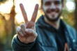 © Guy - Man Showing Peace Sign Victory Gesture Outdoors Close Up Casual Happy