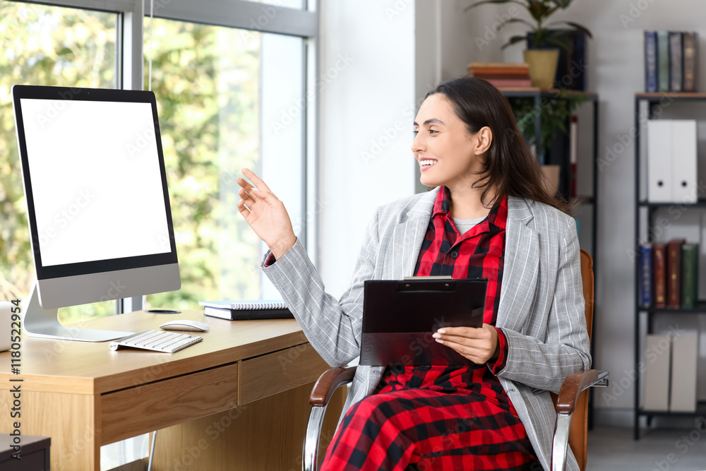 Young businesswoman with clipboard working at table in office. National Wear Your Pajamas to Work Day