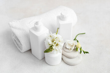 Wall Mural - Set of different cosmetic products, clean towel, spa stones and flowers on light background