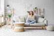 © Pixel-Shot - Beautiful young woman using laptop while sitting on sofa in living room