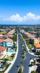 Aerial view of a colorful residential neighborhood with a clear sky and ocean in the background.