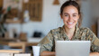 © Ari - Australian woman in army uniform smiling, working with a laptop at tent