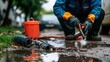 © stockagency - A worker repairing a pipe in a muddy area with tools and equipment nearby.