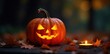 © Andaman - Low angled shot of a glowing pumpkin on black background with fire light, candlelit, autumn leaves