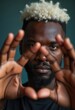 © Giuseppe Cammino - A compelling close-up portrait of an African American man with striking white hair, gazing through his outstretched fingers