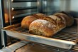 © juliars - Freshly baked loaves of bread cooling on a rack inside a modern oven, showcasing the art of bread making