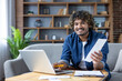 © Liubomir - Portrait of young man with laptop at home, sitting on sofa smiling and looking at camera, paying utility bills, credit checks and bank bills, rent payments.