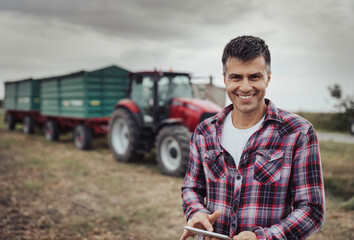 Wall Mural - Farmer with tablet in front of tractor in field