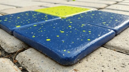 Poster - Closeup of a single tile featuring a deep cobalt blue base with speckles of lime green and sunny yellow. The corners are rounded and a slight sheen suggests it has been treated for