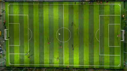 Football or soccer field with green grass and players. Aerial view.