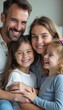 © natakot - A cheerful family of four, including a father, mother, and two young daughters, share a warm embrace, radiating happiness. Their bright smiles and affectionate poses create a heartwarming scene that