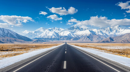 Wall Mural - Endless asphalt road leading to stunning snow-covered mountain peaks under clear skies