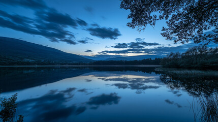 Wall Mural - Calm twilight over mirrored lake with atmospheric cloud reflections and lush surroundings