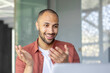 © Liubomir - Video call, young man talking remotely with colleagues and partners, businessman at workplace inside office close up using laptop for remote meeting conference meeting.