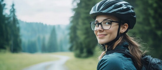 Wall Mural - Smiling female biker in bicycle helmet and glasses, vibrant green countryside, soft natural light, portrait orientation, hills and trees in background.