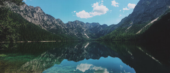 Poster - Majestic mountain range reflects in a serene blue lake under a clear sky