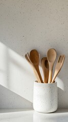 Poster - Wooden spoons, forks, and spatulas stand in a speckled white ceramic container on a speckled white kitchen counter, illuminated by natural light from a nearby window