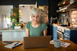 © Marko Geber - Senior woman working on laptop at modern kitchen