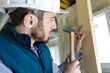 © auremar - male builder knocking nail into wall with hammer