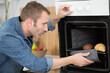© auremar - man taking out tray of croissants from oven