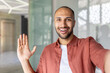 © Liubomir - Joyful man looking into phone camera, talking to colleagues and partners remotely using video call, office worker at workplace inside office.