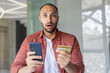 © Liubomir - Portrait of disappointed and deceived man, holding bank credit card and phone in hands, account blocked and money transfer refused. Fraudulent actions.