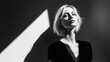 artistic black and white fashion portrait of elegant blonde model in minimalist setting with strong geometric elements and shadow play