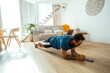 © simona - Middle-aged man doing a plank workout on a wooden floor in his living room, following an online fitness lesson through his phone to maintain his healthy lifestyle and improve his overall well-being