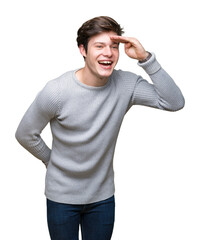 Wall Mural - Young handsome man wearing winter sweater over isolated background very happy and smiling looking far away with hand over head. Searching concept.