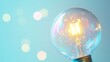© Fenny - Glowing lightbulb on blue bokeh background.