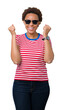 © Krakenimages.com - Beautiful young african american woman wearing sunglasses over isolated background celebrating surprised and amazed for success with arms raised and open eyes. Winner concept.