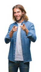 Young handsome man with long hair over isolated background pointing fingers to camera with happy and funny face. Good energy and vibes.