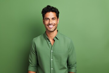 studio portrait of a cheerful young man wearing a green shirt, smiling against a green background