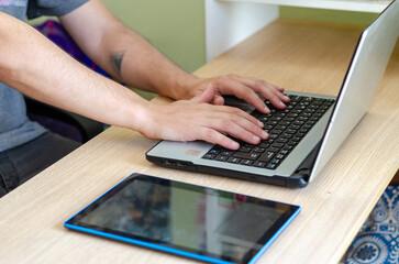 Young male employee or student writing in a laptop close up no face