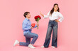 © Home-stock - Guy standing on one knee with flowers and gift for Valentine's Day while offended lady rejecting him, standing on pink background