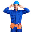 © Krakenimages.com - Young handsome man wearing worker uniform and hardhat doing peace symbol with fingers over face, smiling cheerful showing victory