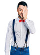 © Krakenimages.com - Hispanic man with beard wearing hipster look with bow tie and suspenders covering one eye with hand, confident smile on face and surprise emotion.