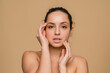 © InsideCreativeHouse - Woman with beautiful face touching healthy facial clean skin. Attractive smiling hispanic latin model with natural makeup enjoys glowing hydrated skin on beige background closeup. Skincare beauty .