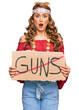 © Krakenimages.com - Young blonde girl wearing hippie style holding no guns warning banner scared and amazed with open mouth for surprise, disbelief face