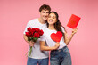 © Home-stock - Valentine's Day concept. European couple in love posing with bouquet of flowers, red paper heart-shaped and greeting card isolated on pink studio background