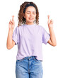 © Krakenimages.com - Beautiful kid girl with curly hair wearing casual clothes gesturing finger crossed smiling with hope and eyes closed. luck and superstitious concept.